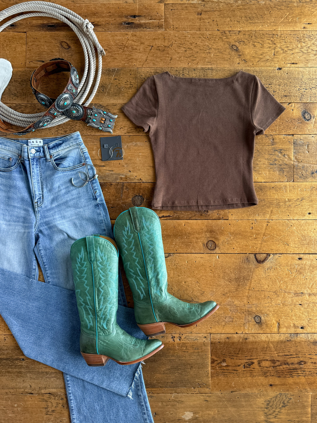 The Almera by Savannah Sevens western life{&}style: light blue jeans, green cowboy boots, a buttery soft cocoa tri-blend short sleeve top, turquoise-accented belt, and silver earrings—perfect for a Western vibe.