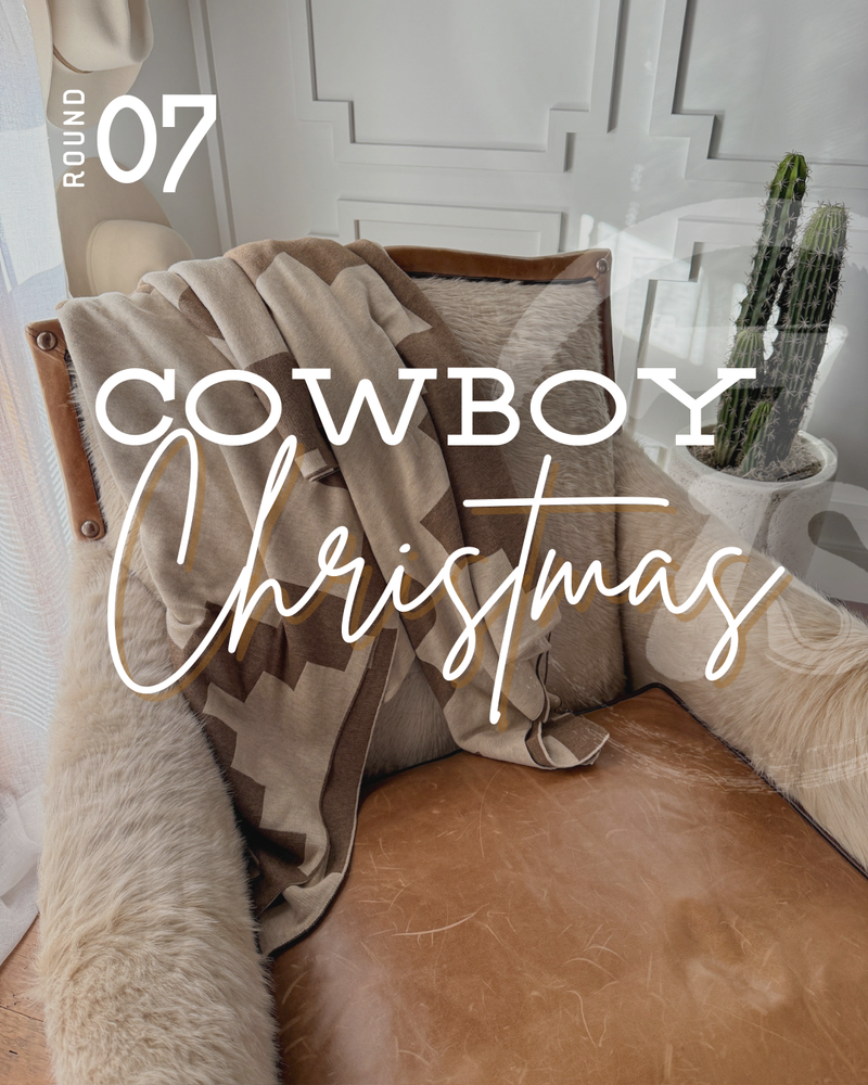 A cozy tan chair with a fur throw, a patterned blanket, and a cushion sits by a window next to a potted cactus. Overlay text reads Round 07 Cowboy Christmas, adding a warm western charm to the inviting scene.