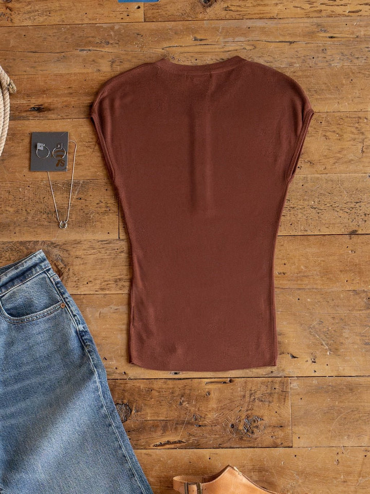 The Adair Chestnut Cap Sleeve Top by Savannah Sevens western life{&}style is laid flat on a wooden floor, surrounded by partially visible blue jeans, a necklace, earrings, and tan shoes.