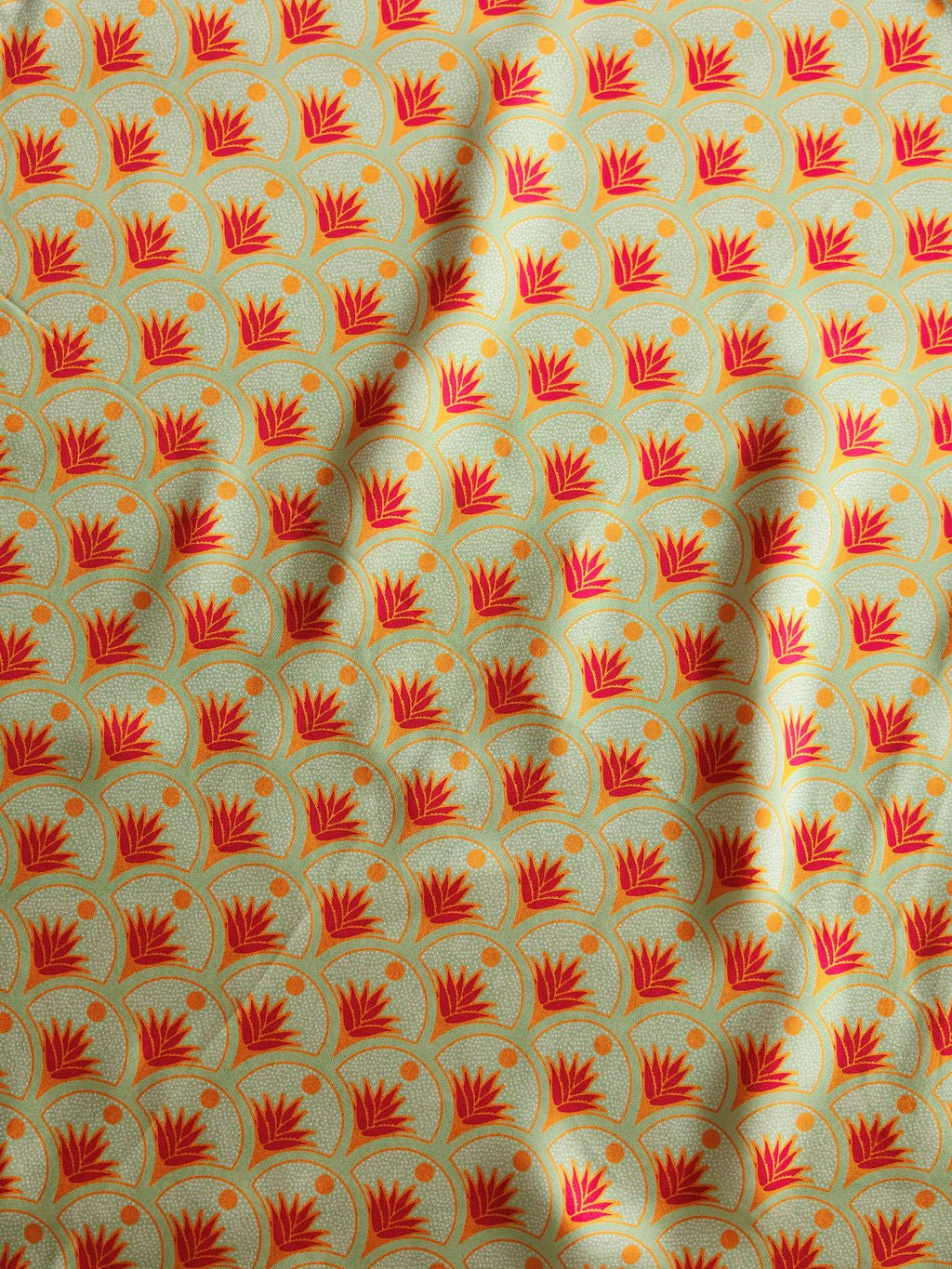 The Agave Neck Scarf by Savannah Sevens western life{&}style features red and orange stylized flowers with yellow dots on light green, in a hand drawn pattern with soft folds—perfect for adding artistic flair to your look.