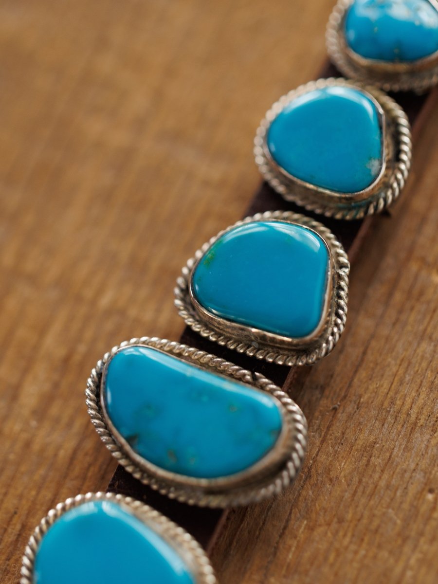 Close-up of the Aguila Bracelet by Savannah Sevens western life{&}style, featuring five genuine turquoise stones set in sterling silver on leather, shown resting on a wooden surface.