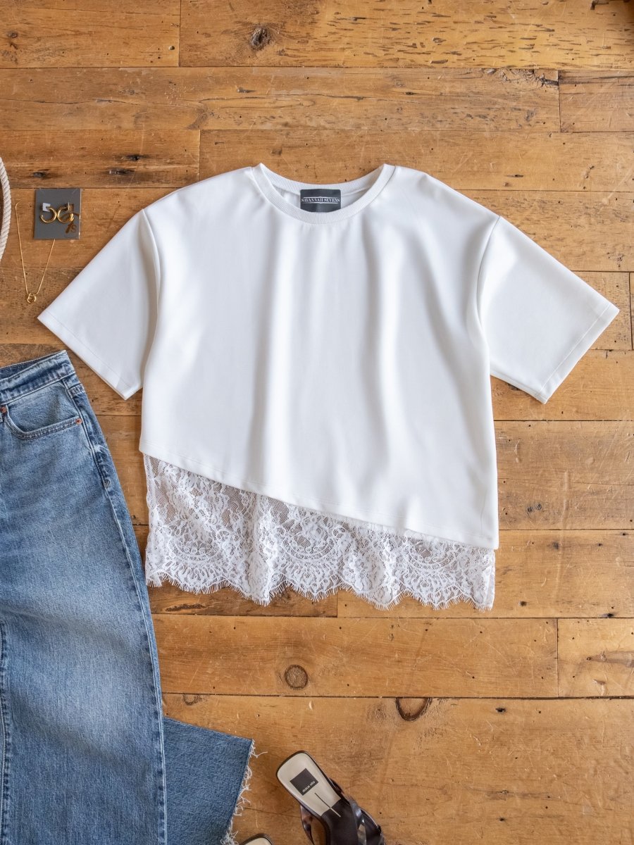 The Arivaca White Lace Hem Top by Savannah Sevens western life{&}style is laid flat on a wooden surface beside blue denim jeans, a gold bracelet, sunglasses, and a brown sandal.