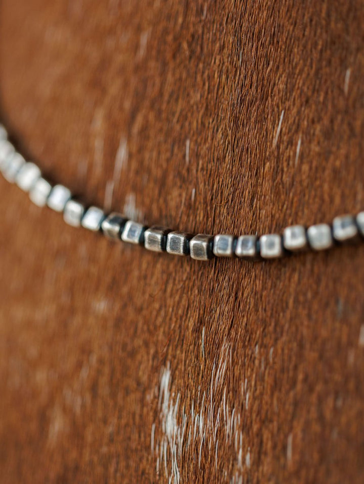 A close-up of the Atoka Necklace by Savannah Sevens western life{&}style, a sterling silver Navajo pearl piece, resting on brown animal fur with white patches visible.