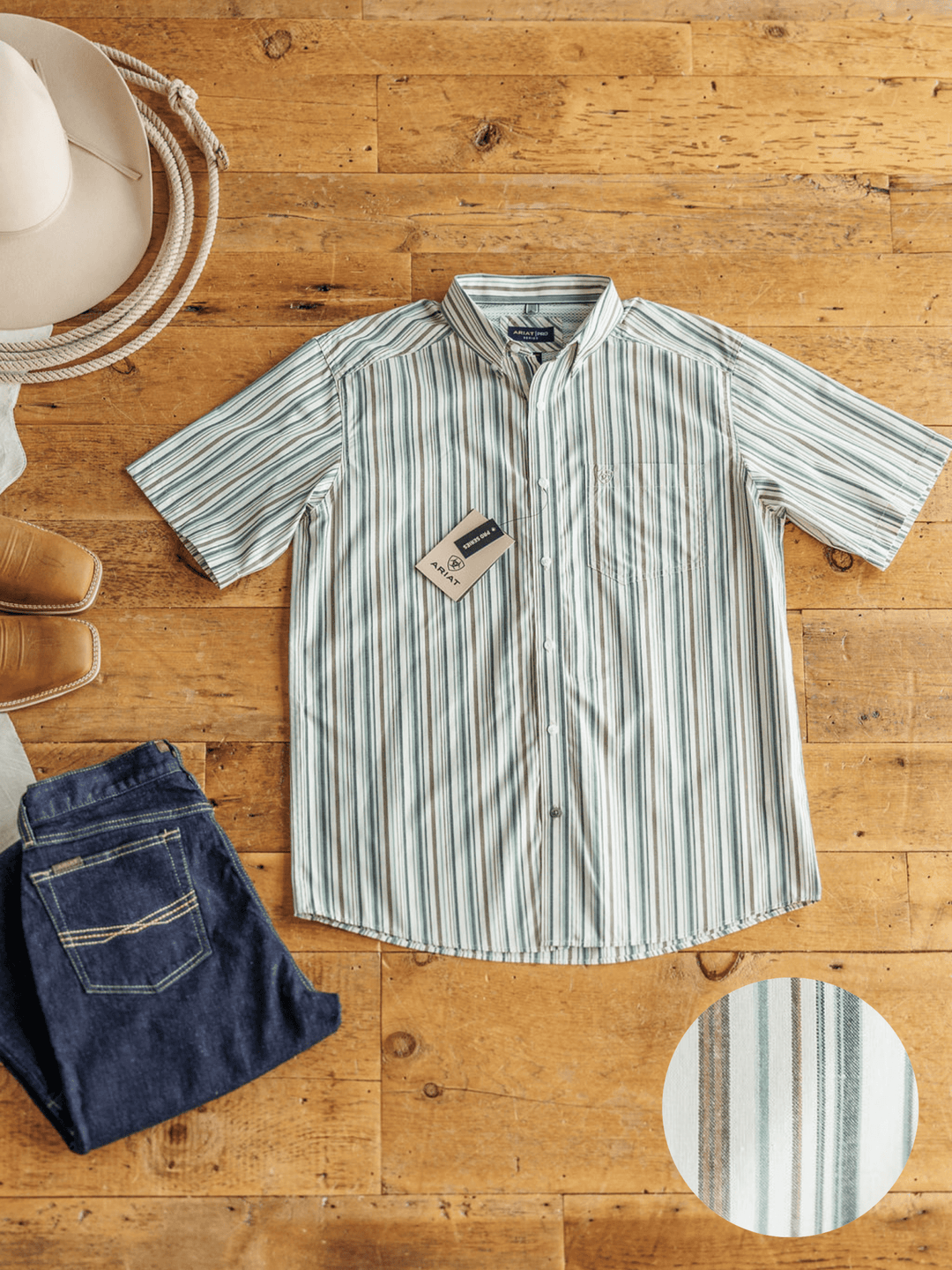 A Savannah Sevens western life{&}style Austwell Ariat Men's Pinstripe Button Up in green and white is laid on a wooden floor with blue jeans, brown cowboy boots, and a cowboy hat. An inset shows the shirt’s moisture wicking pinstripe fabric.