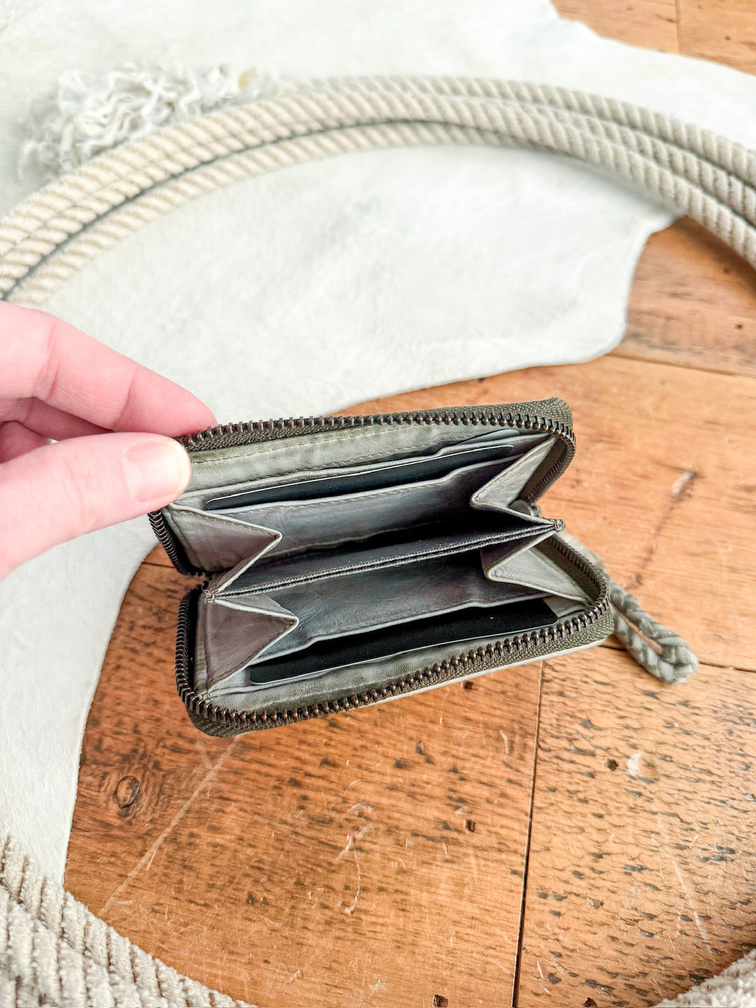 A hand displays the Avoca Wallet by Savannah Sevens western life{&}style above a wooden surface, with a coiled rope and white textured cloth in the background.