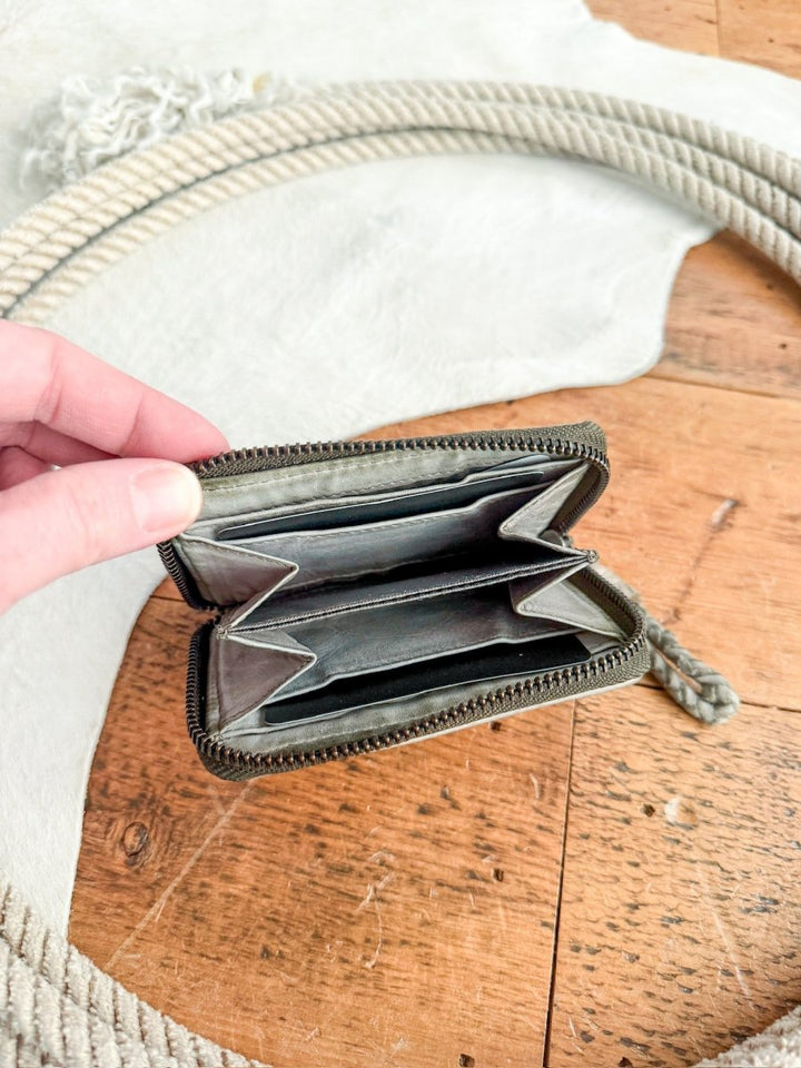 A hand displays the Avoca Wallet by Savannah Sevens western life{&}style above a wooden surface, with a coiled rope and white textured cloth in the background.