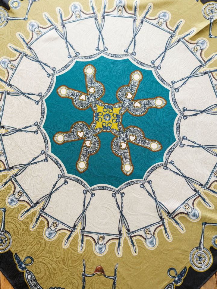 The Bits Wild Rag {Teal} by Savannah Sevens western life{&}style is a vibrant jacquard silk scarf with scissors and ornate keys in a kaleidoscopic paisley design, featuring teal, white, and gold for a luxurious statement.