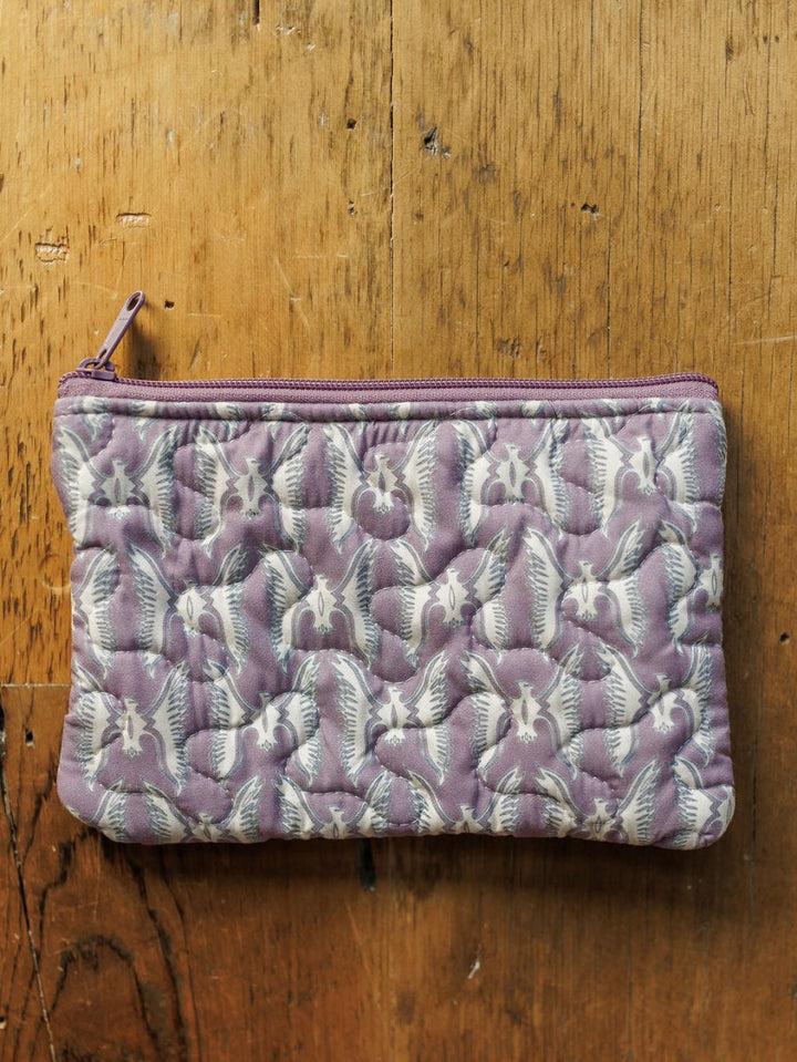 A small handmade quilt pouch with a purple zipper and white bat pattern rests on wood. Part of the Boots Collection by Savannah Sevens western life{&}style.