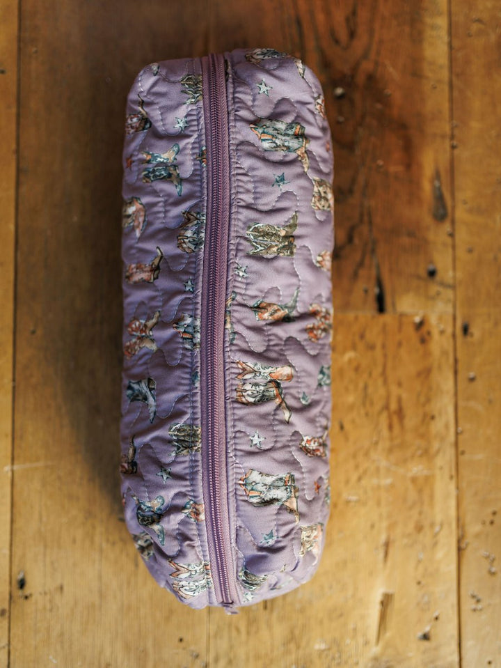 The Boots Collection by Savannah Sevens western life{&}style, a quilted purple bag set with a zippered pouch featuring a playful cat pattern, is displayed on a wooden surface.