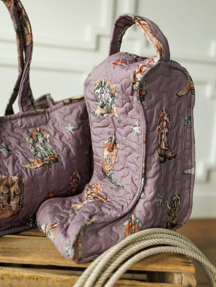 The Boots Collection by Savannah Sevens western life{&}style features a lavender quilted bag set with cowboy boot print, displayed with a matching tote and rope from our western travel line, against a white paneled wall.