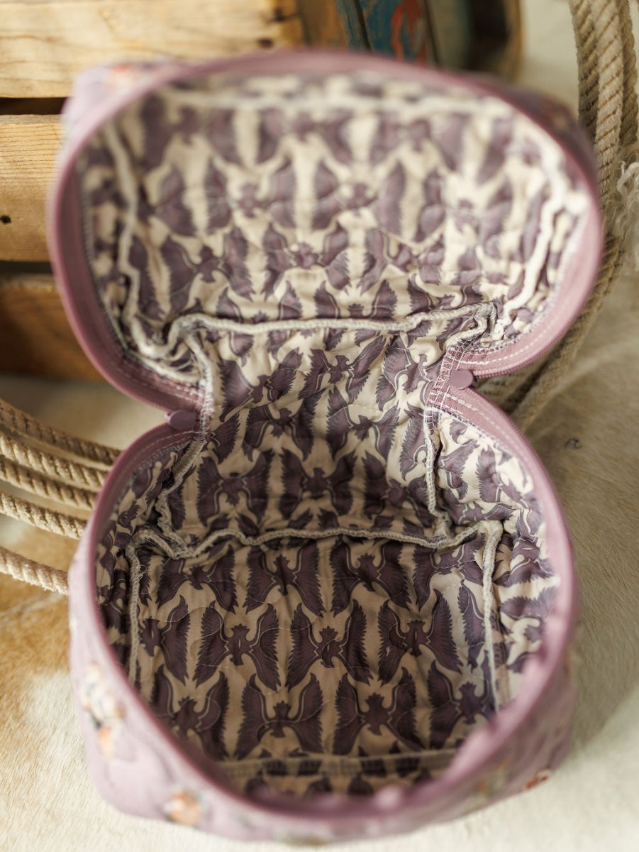 Open, empty fabric pouch from the Boots Collection by Savannah Sevens western life{&}style, with a light purple interior and dark purple birds in flight pattern. Part of a quilted bag set, displayed on cream surface beside rope and wooden boxes.