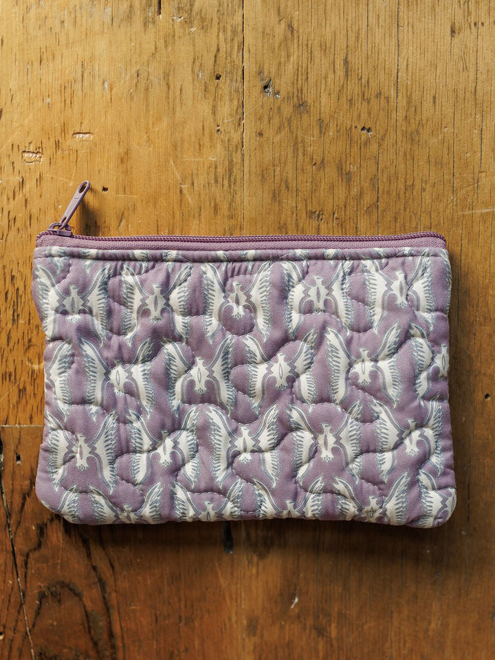 A small handmade quilt pouch with a purple zipper and white bat pattern rests on wood. Part of the Boots Collection by Savannah Sevens western life{&}style.