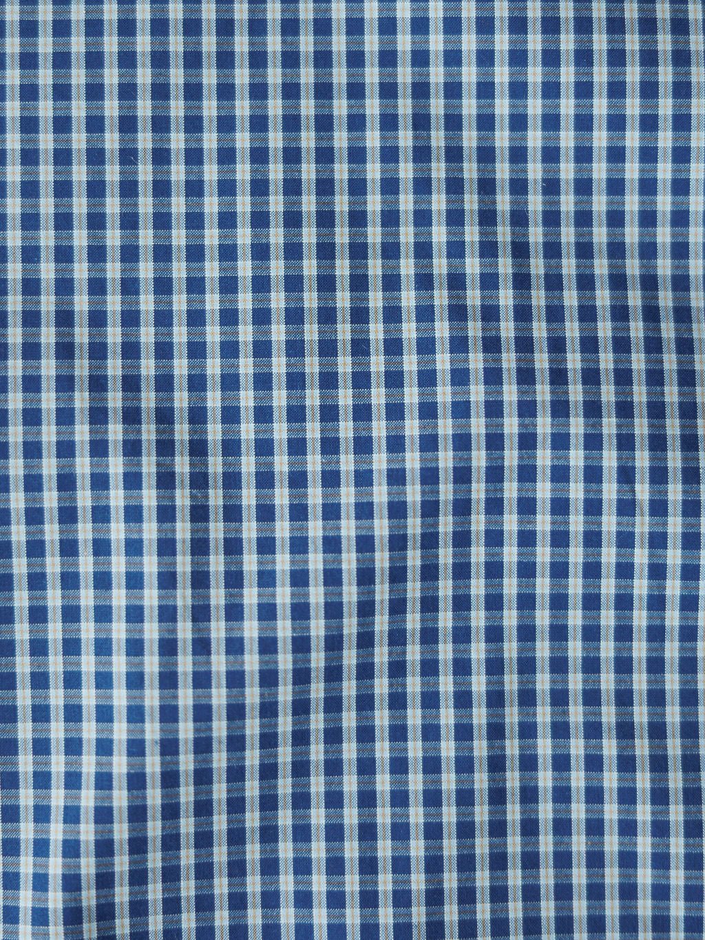 Close-up of blue and white checkered fabric shows the textured grid pattern and wrinkles of the Brentwood Ariat Men's Blue Plaid Pearl Snap shirt by Savannah Sevens western life{&}style, featuring classic vertical and horizontal lines.
