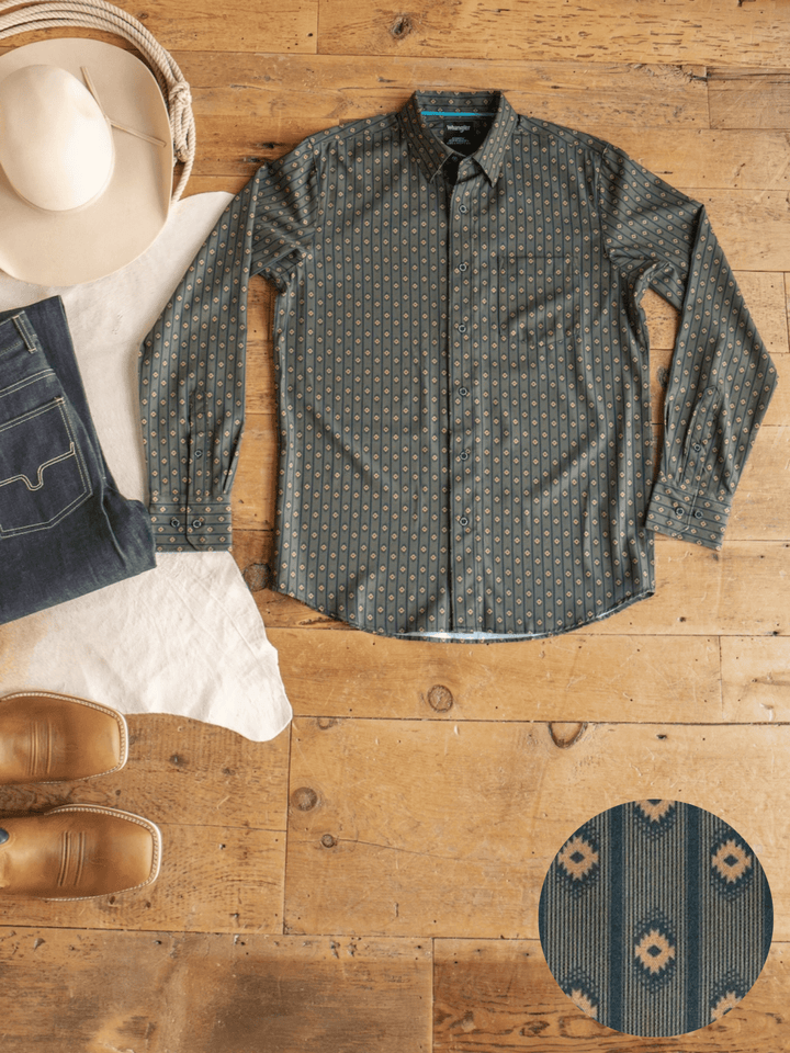 The Brigham Wrangler Men's Southwest Button Up from Savannah Sevens western life{&}style, featuring a green geometric southwest pattern, is laid flat on a wooden floor alongside blue jeans, a white hat, brown boots, and a woven bag. A close-up showcases the unique design details of this Wrangler button up.