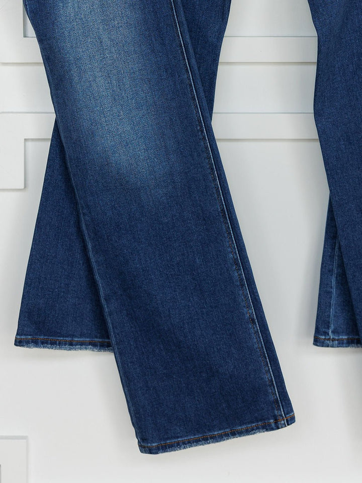 A close-up of The Bristol High Rise 90's Wide Leg Jean by Savannah Sevens western life{&}style in dark blue shows slight fading and visible hems, with the wide legs hanging against a white background.