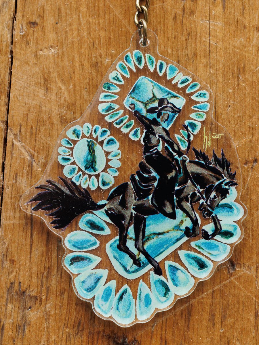 The Bronc Keychain by Savannah Sevens western life{&}style features hand drawn artwork of a black armored knight on horseback, turquoise gemstone accents, and a wooden background—a unique Western purse charm.