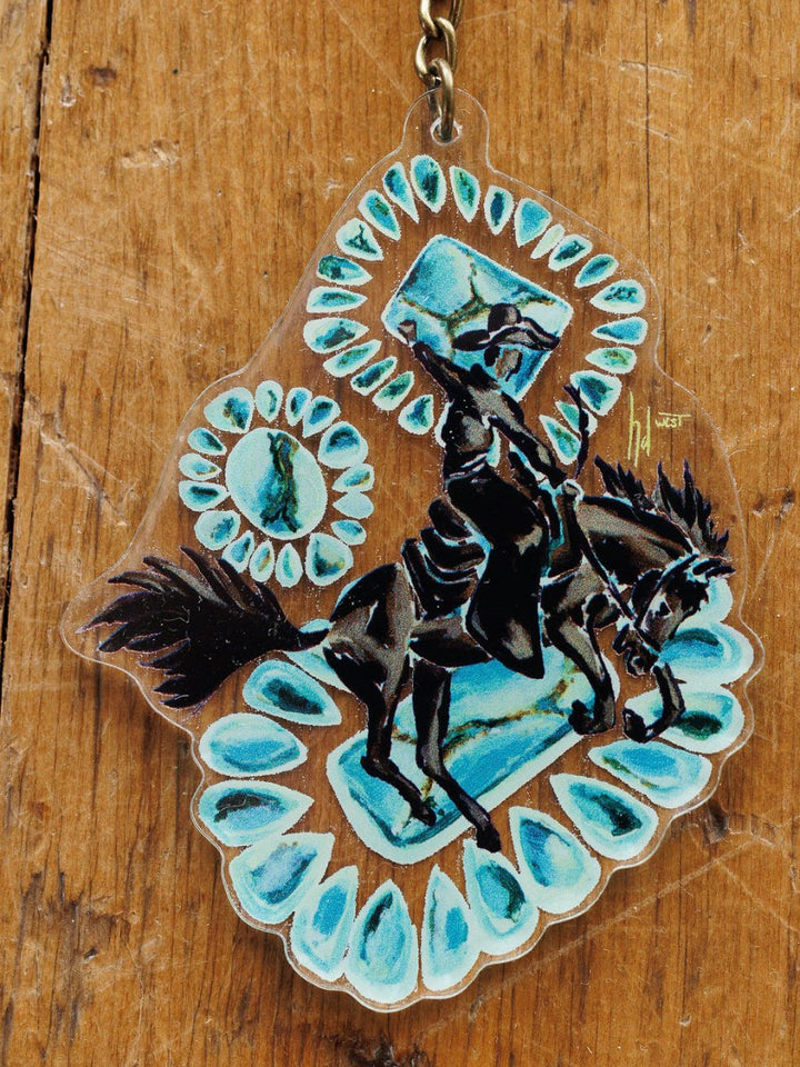 The Bronc Keychain by Savannah Sevens western life{&}style features hand drawn artwork of a black armored knight on horseback, turquoise gemstone accents, and a wooden background—a unique Western purse charm.