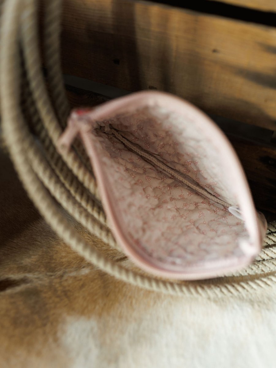 An open small pink pouch from the Brumby Rose Collection by Savannah Sevens western life&style, showing a subtle inner pattern, viewed from above on a beige rope and wooden surface.