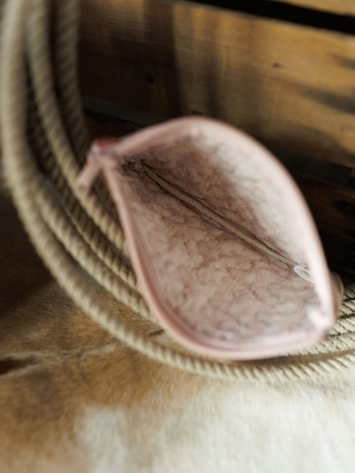 An open small pink pouch from the Brumby Rose Collection by Savannah Sevens western life&style, showing a subtle inner pattern, viewed from above on a beige rope and wooden surface.