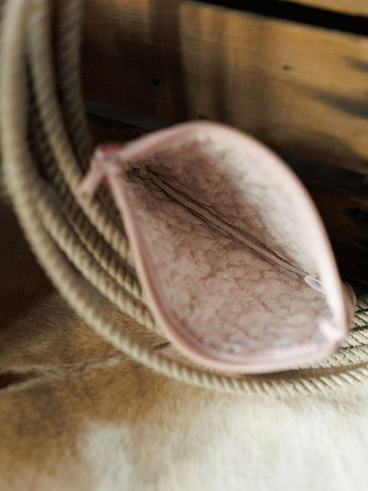 An open small pink pouch from the Brumby Rose Collection by Savannah Sevens western life&style, showing a subtle inner pattern, viewed from above on a beige rope and wooden surface.