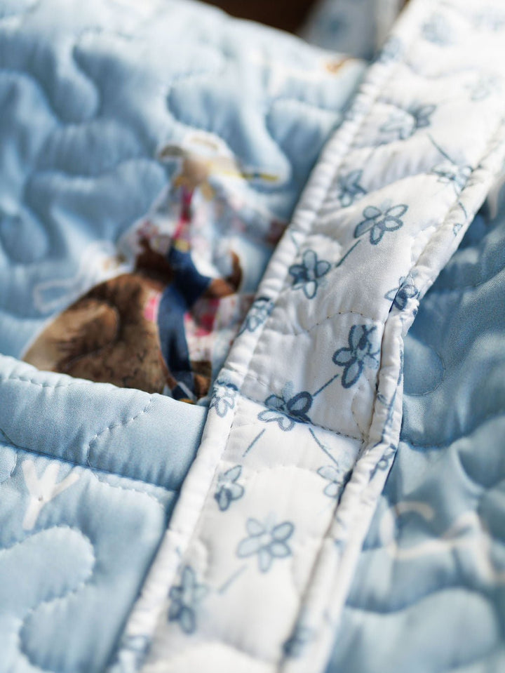 Close-up of a blue quilted fabric with a white, floral-patterned strip from the Brumby Sky Collection by Savannah Sevens western life&style.  By Ida Mae. 