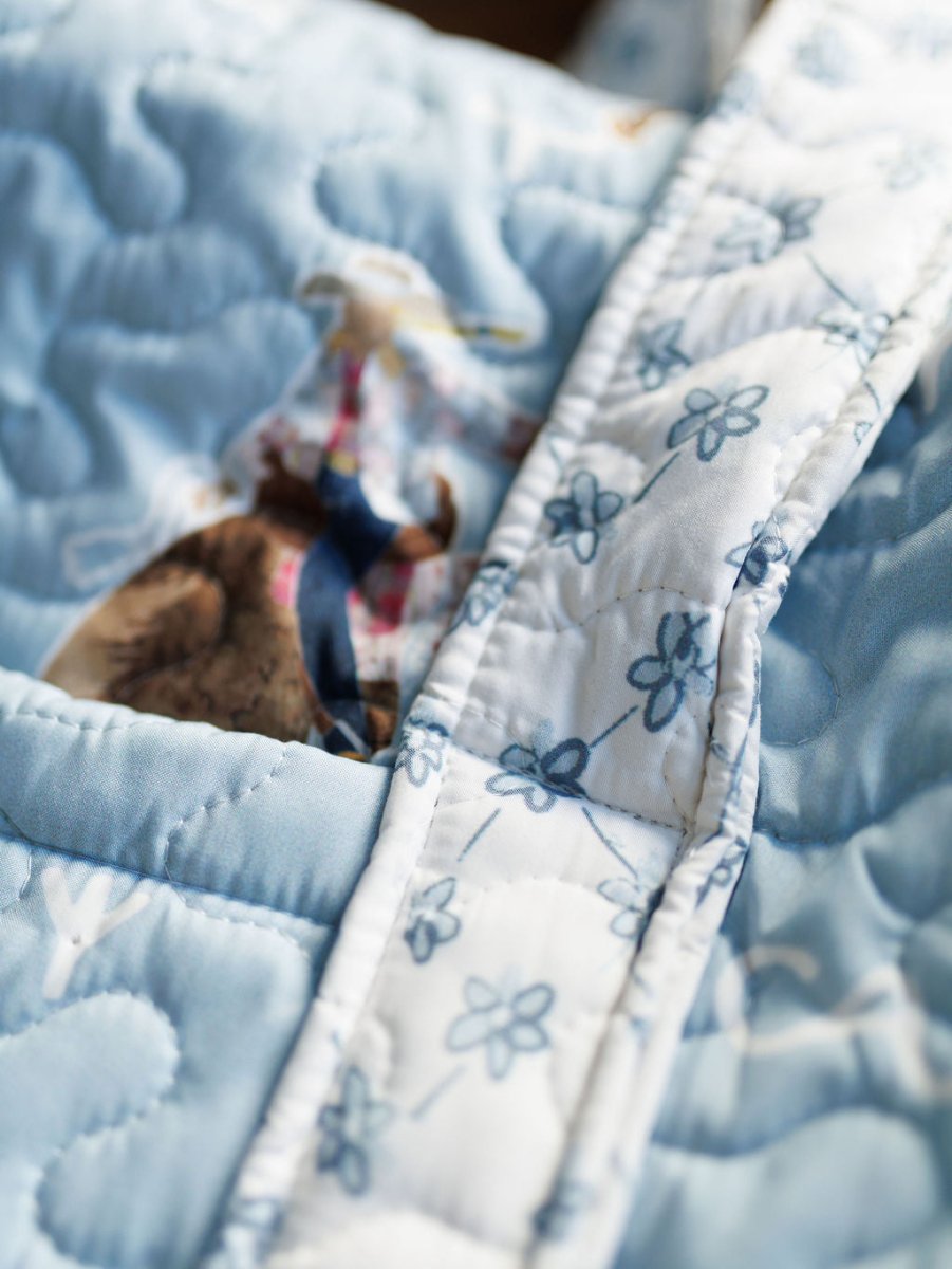 Close-up of a blue quilted fabric with a white, floral-patterned strip from the Brumby Sky Collection by Savannah Sevens western life&style.  By Ida Mae. 