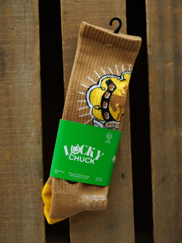 A pair of Bucking Cowgirl Crew Socks by Savannah Sevens western life{&}style, featuring a cartoon lion design and green Lucky Chuck label, shown on a wooden surface.