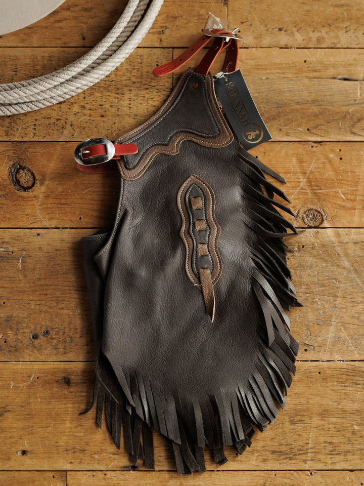 The Buffalo Chinks {Youth} by Savannah Sevens western life{&}style is a handmade dark brown leather chink with decorative stitching, red strap, and tag—ideal for youth and cowboy chaps fans.