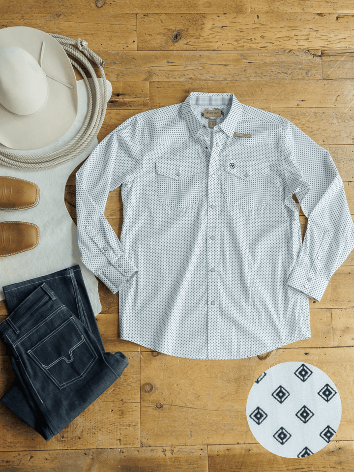 The Burke Ariat Men's Southwest Pearl Snap by Savannah Sevens western life{&}style, a white long-sleeve geometric print shirt, is laid flat on wood with a white cowboy hat, tan boots, blue jeans, and a close-up of its unique pattern in the corner.