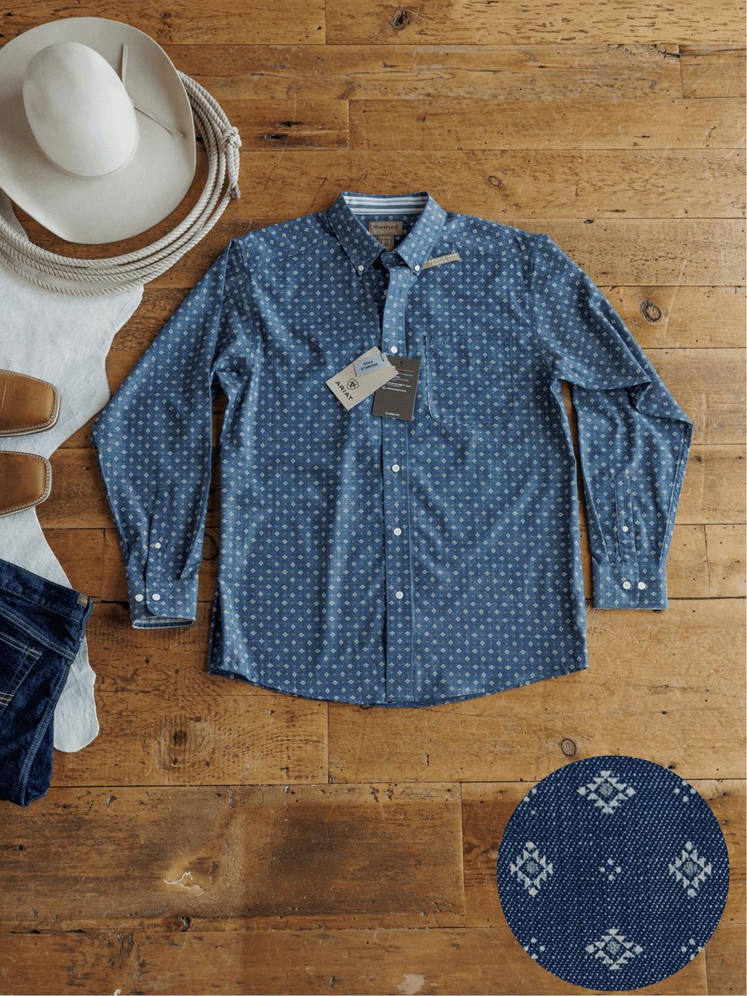 The Burleson Ariat Men's Southwest Button Up from Savannah Sevens western life{&}style is laid flat on a wooden floor with a white cowboy hat, brown shoes, and jeans. An inset shows off its geometric southwest pattern.