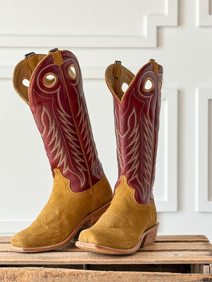 A pair of Caldwell Tan Men’s Western Leather Boots by Savannah Sevens western life{&}style, featuring tan suede lower halves, maroon leather uppers, and decorative stitching, sit on a wooden pallet against a white wall with rectangular patterns. Boots by HYER. 