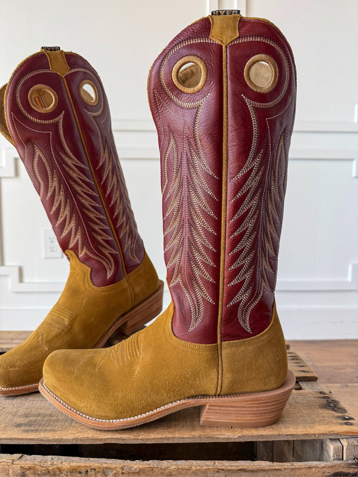 A pair of Caldwell Tan Men’s Western Leather Boots by Savannah Sevens western life{&}style, showcasing a tan suede foot and maroon leather shaft with intricate stitching and circular cutouts near the top, displayed on a wooden pallet. Boots by HYER. 