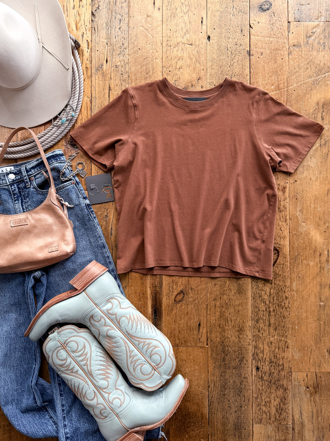 A caramel-colored, feminine fit Campbell Caramel Basic Tee by Savannah Sevens western life&style laid flat next to blue jeans, a beige hat, a small handbag, and light blue cowboy boots.