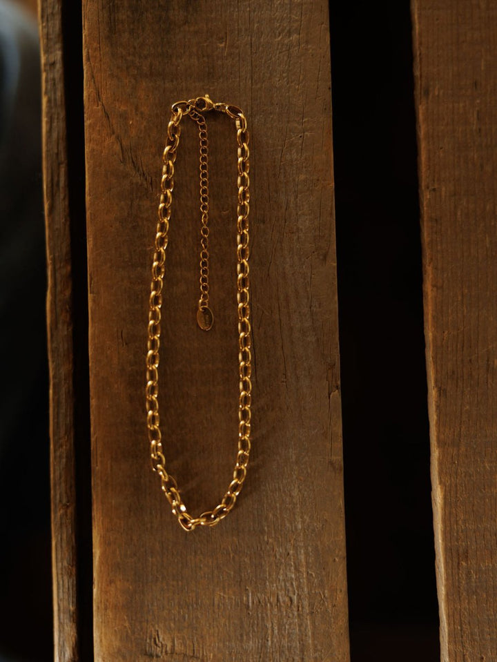 The Cheney Necklace by Savannah Sevens western life{&}style is a waterproof gold choker with an extender clasp, shown flat on rustic wood. Effortlessly elegant, it’s perfect for any look.