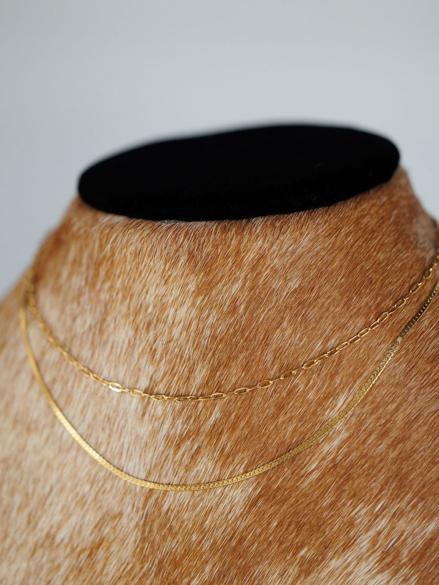 The Chenoa Necklace by Savannah Sevens western life{&}style—two delicate 18K gold filled, hypoallergenic pieces—are displayed on a bust draped in light brown animal fur with a black velvet top, with a softly blurred background.
