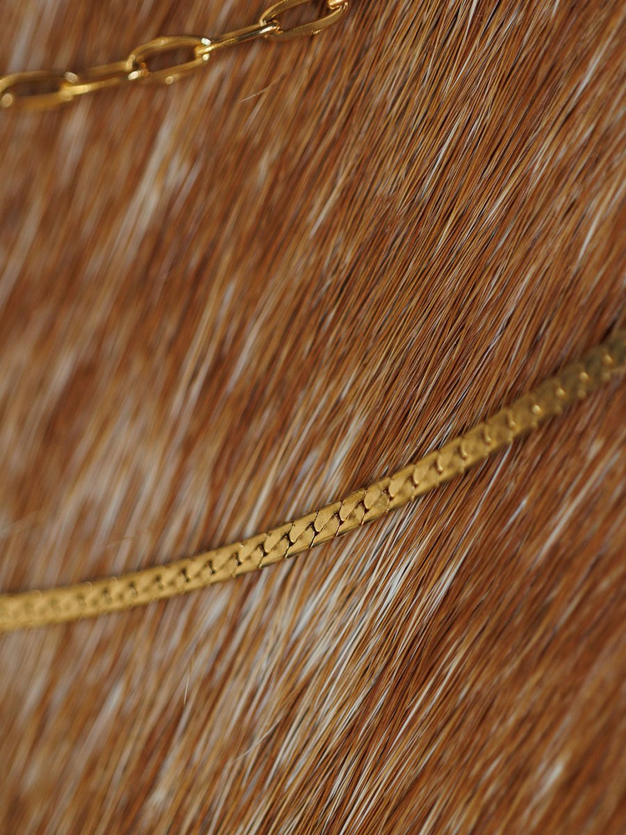 Close-up of two Savannah Sevens western life{&}style Chenoa Necklaces, featuring 18K gold filled chains gently curving over a brown and white fur surface.