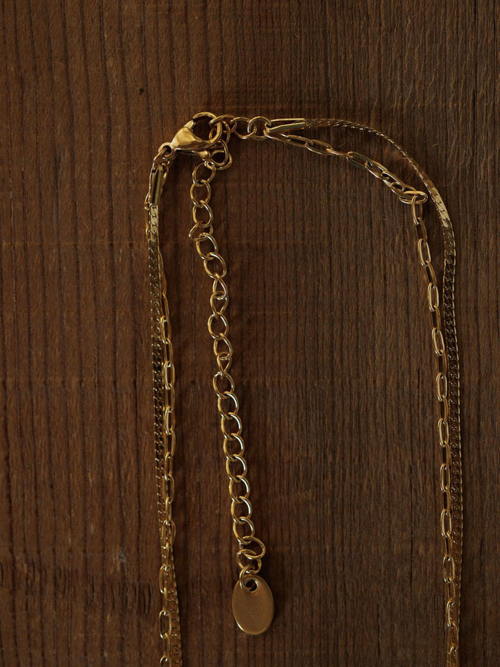 The Chenoa Necklace by Savannah Sevens western life{&}style is an 18K gold filled, hypoallergenic choker with an adjustable clasp and small oval pendant, shown on a textured wooden surface.