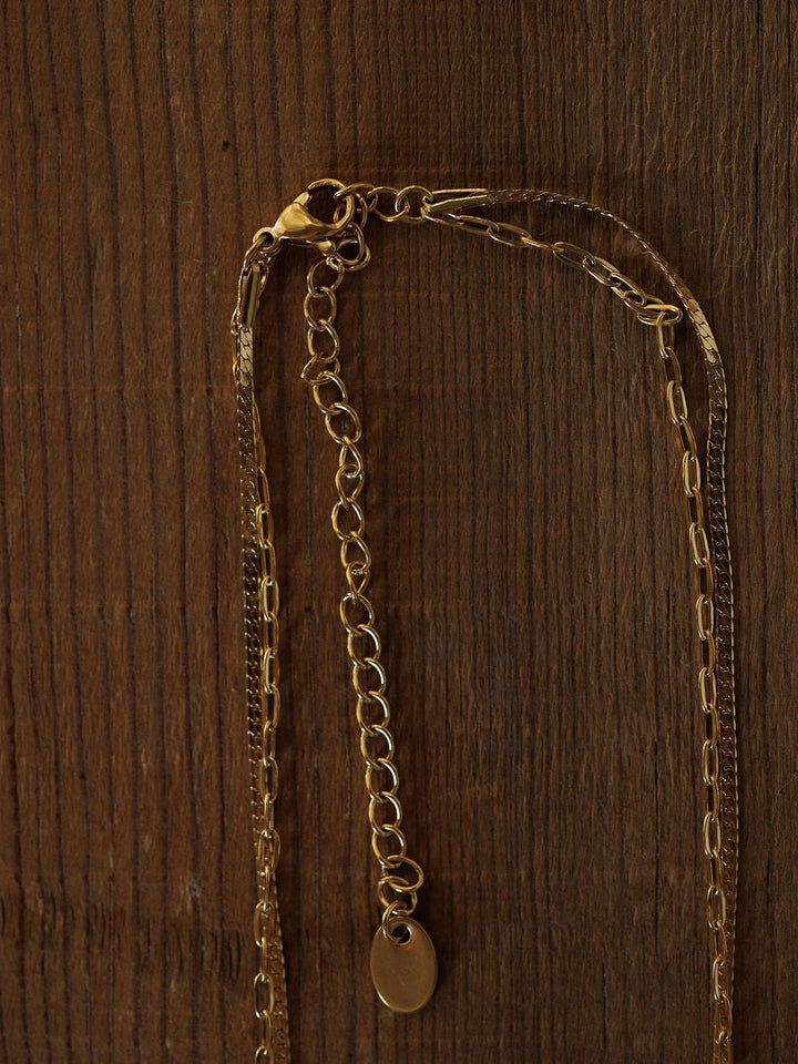 The Chenoa Necklace by Savannah Sevens western life{&}style is an 18K gold filled, hypoallergenic choker with an adjustable clasp and small oval pendant, shown on a textured wooden surface.