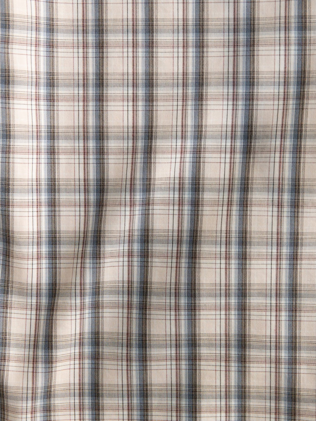 A close-up of the Clifton Ariat Men's Plaid Button Up by Savannah Sevens western life{&}style, featuring beige wrinkle-free fabric with intersecting blue, brown, and red lines for a crisp plaid look.