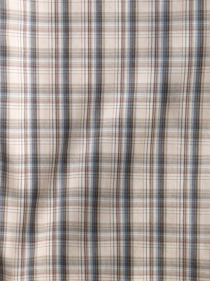 A close-up of the Clifton Ariat Men's Plaid Button Up by Savannah Sevens western life{&}style, featuring beige wrinkle-free fabric with intersecting blue, brown, and red lines for a crisp plaid look.