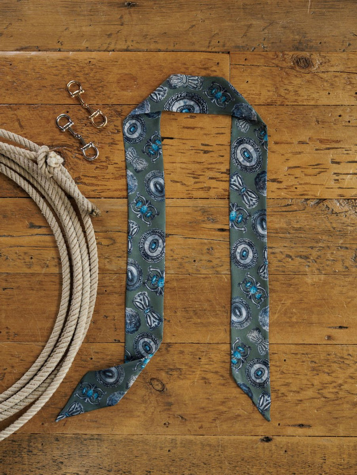 The Concho Twilly {Sage} by Savannah Sevens western life{&}style, along with a coiled rope and three small metal clasps, is displayed on a rustic wooden surface.