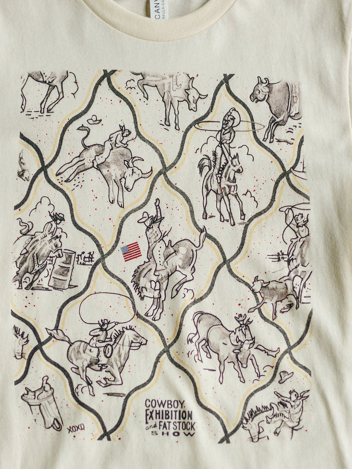 The Cowboy Exhibition tee by Savannah Sevens western life{&}style is cream-colored and features line-drawn cowboys riding bulls, roping cattle, rodeo tricks, an American flag, and the text COWBOY EXHIBITION and FAT STOCK SHOW.