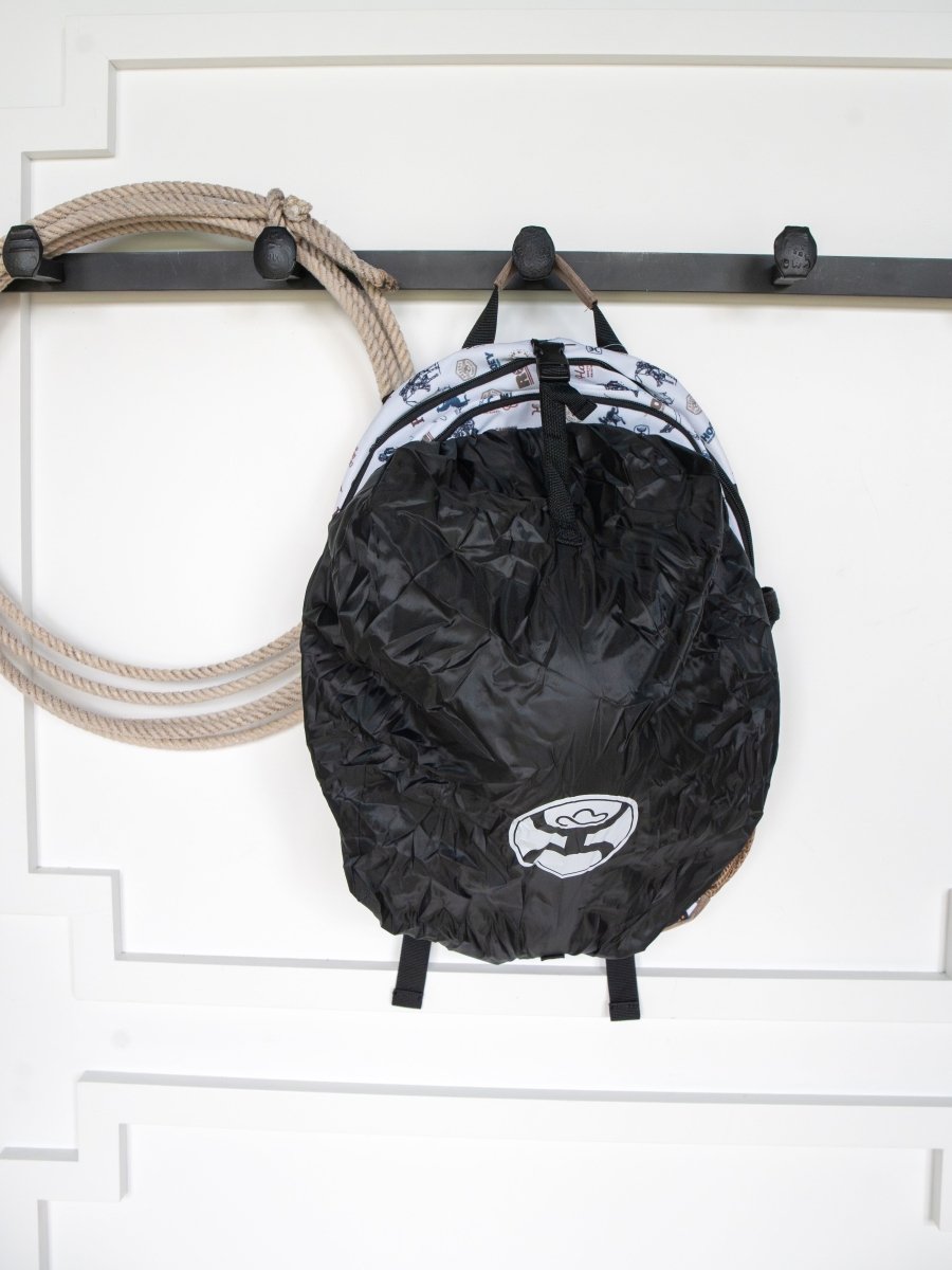 The Cowboy Golf Medium Canvas Hat Holder Backpack by Savannah Sevens western life{&}style hangs on a hook next to a Hooey hat holder and coiled beige rope against a white paneled wall.
