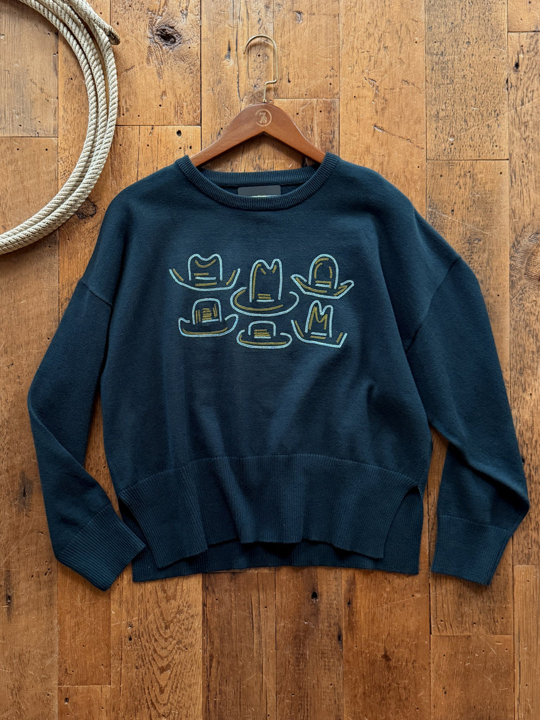 Savannah Sevens western life&style Cowboy Hat Deep Teal Embroidered Sweater in deep teal cotton blend featuring an embroidered western graphic pattern of five different cowboy hats in yellow and light blue.