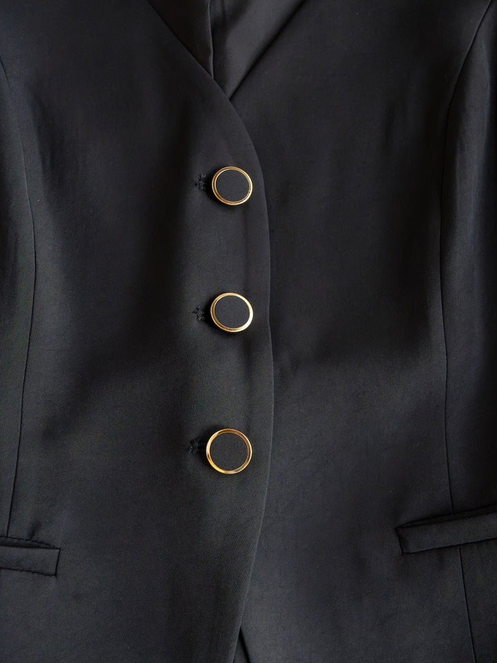 Close-up of the Cuero Black Vest Set by Savannah Sevens western life{&}style, featuring matte satin fabric, three vertically arranged black buttons with gold rims, and two horizontal front pockets.