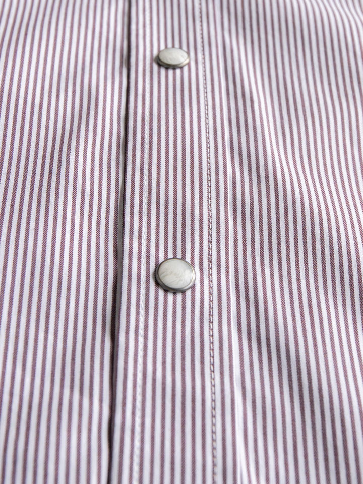 Close-up of the Savannah Sevens western life{&}style Cutler Cinch Men's Pinstripe Pearl Snap shirt, showcasing thin vertical purple and white stripes and two round pearl snap buttons on the placket.