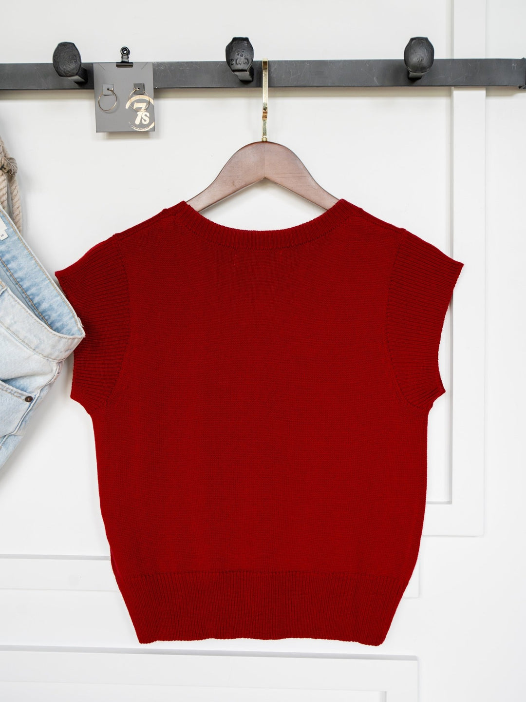 The Dacoma Cherry Red Knit Top by Savannah Sevens western life{&}style, shown on a hanger next to light blue jeans, features cap sleeves and a wool blend knit. Available in young contemporary sizing.