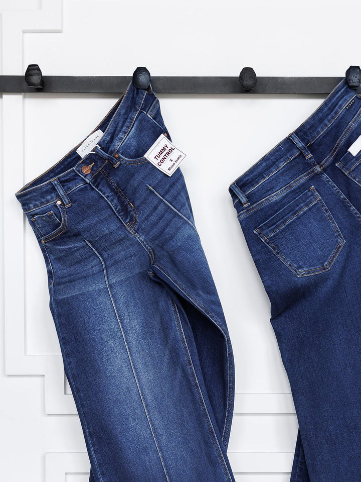Two pairs of blue jeans hang on black hooks against a white wall, including The Dakota High Rise Wide Leg Crop Jean by Savannah Sevens western life{&}style. Both feature classic stitching and front and back pockets; one pair has a Tommy Hilfiger label.