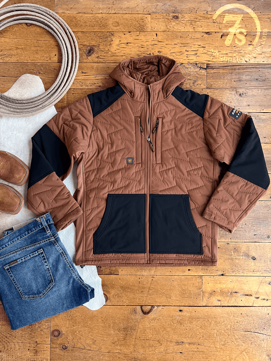 The Davenport Ariat Men's Insulated Jacket by Savannah Sevens western life{&}style is shown laid flat on a wooden floor with blue jeans, brown slip-on shoes, a white rug, and the 7S ranch logo in the top right corner.