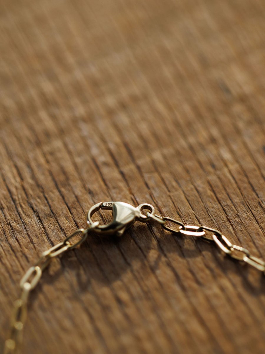 A close-up of the Diamond Horseshoe Bracelet by Savannah Sevens western life{&}style, crafted in 14K yellow gold with a lobster clasp, displayed on a textured wooden surface.